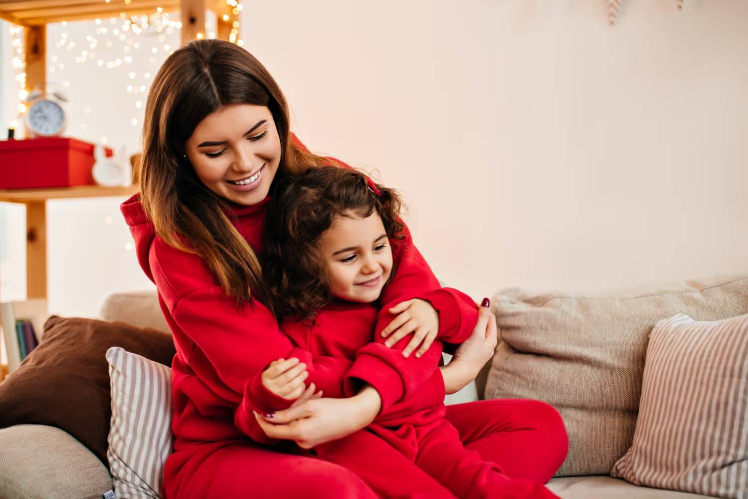 A mother hugging her young daughter on a sofa